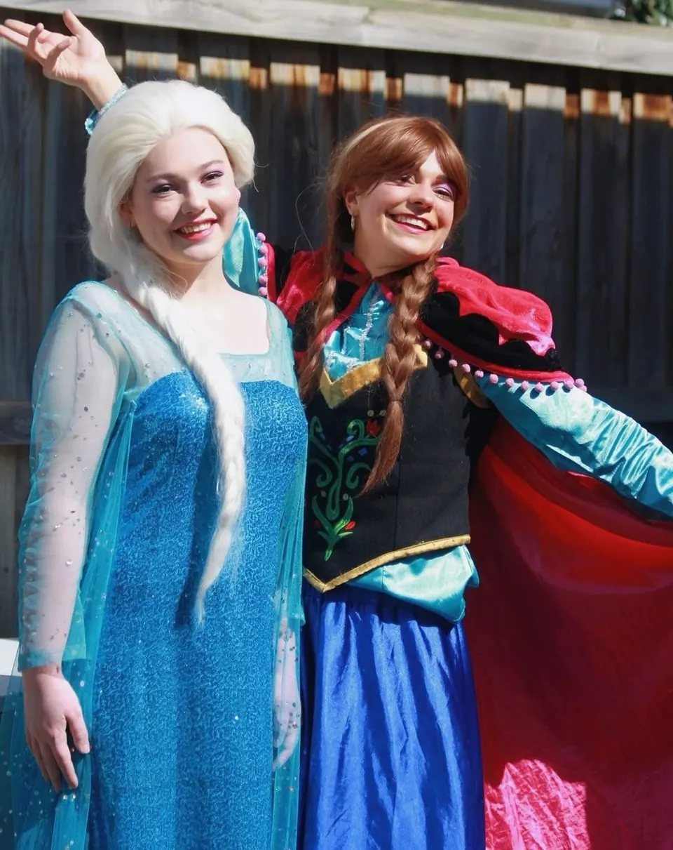 Frozen Elsa and Anna sister party entertainers in matching Disney costumes posing together in a sunny Melbourne backyard birthday party