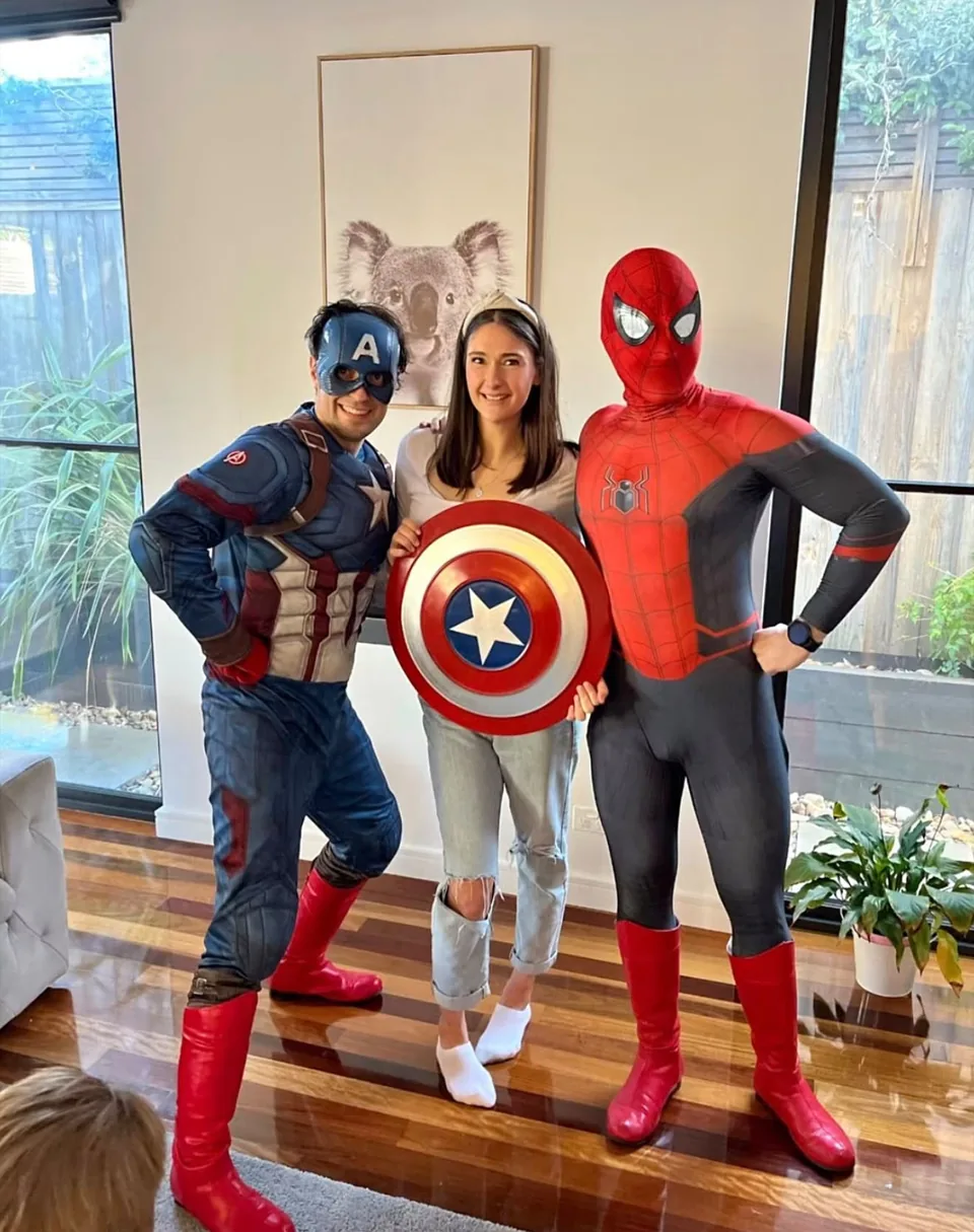 Captain America and Spider-Man party entertainers posing with smiling mum holding Captain America shield in a Melbourne living room at a superhero themed kids birthday party