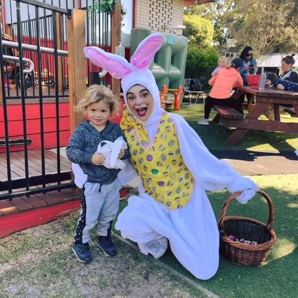 Easter bunny party mascot kneeling with toddler in playground holding chocolate egg basket at a Melbourne Easter kids party