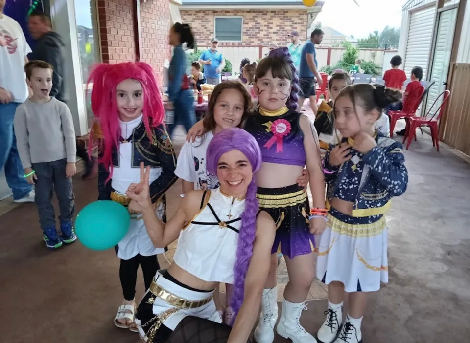 K-Pop Demon Hunters Rumi, Zoey and Mira party entertainers with group of young girls in matching Huntr/x costumes at a Melbourne backyard K-Pop Demon Hunters birthday party