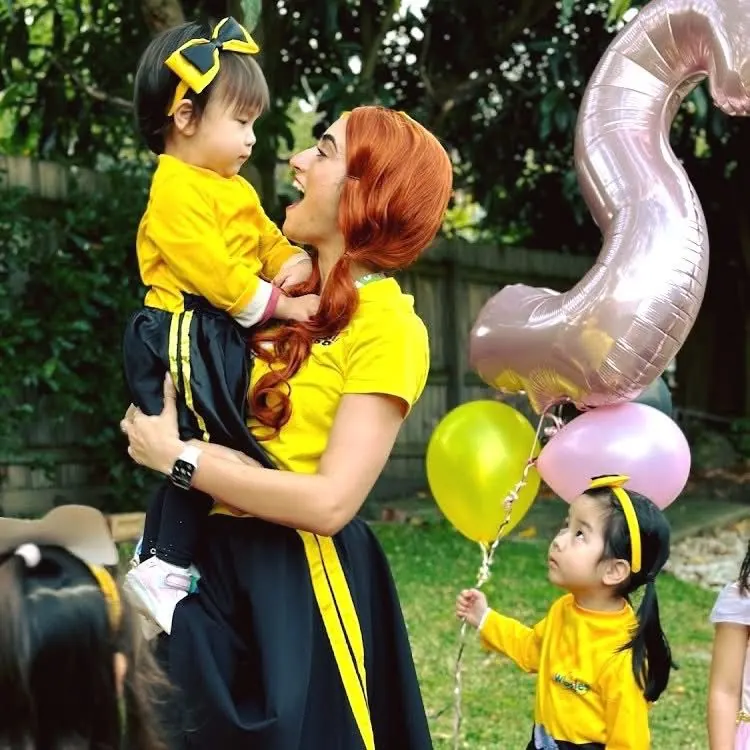 Emma Wiggle entertainer holding toddler with another child watching, pink number 5 balloon at a Wiggles-themed Melbourne 5th birthday party