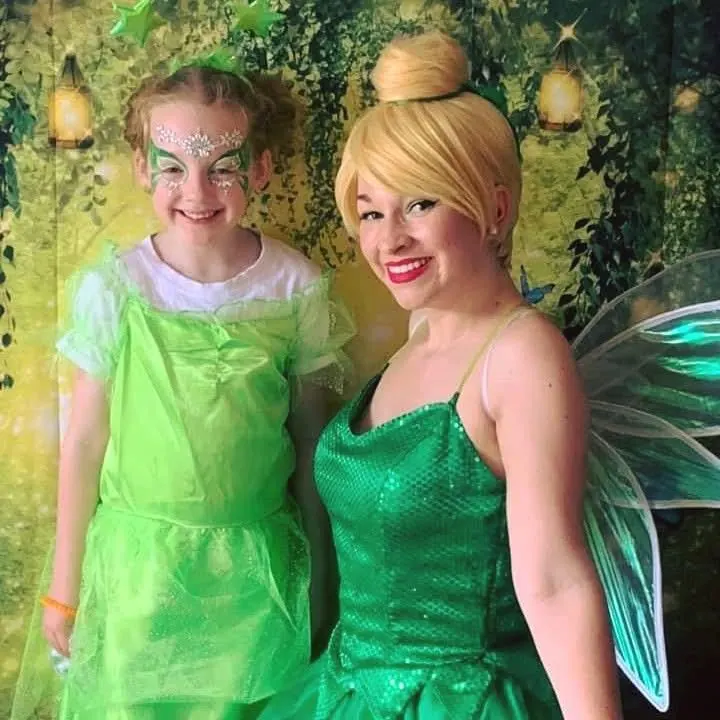 Tinkerbell fairy party entertainer with green wings posing with girl in matching green fairy dress and sparkly face paint in Melbourne