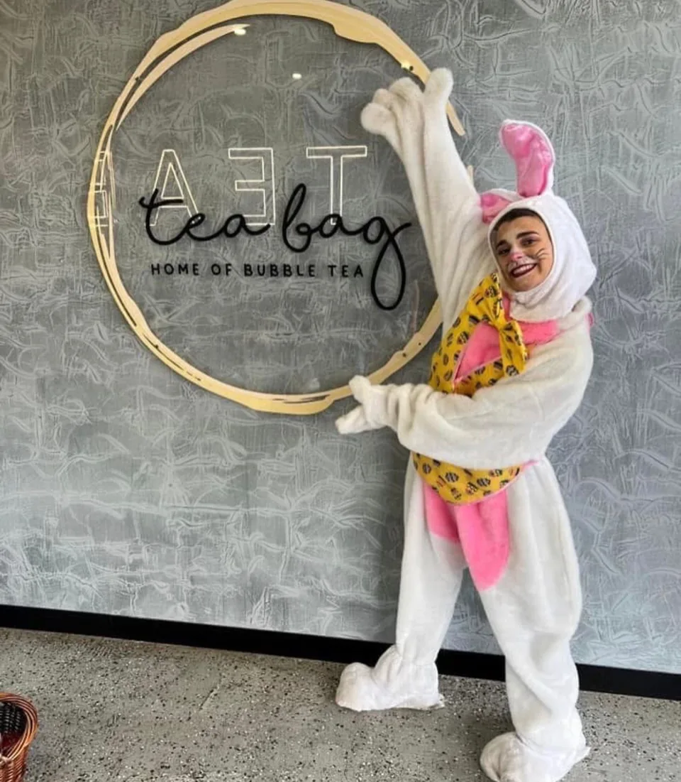 Easter bunny party mascot in pink and white costume waving at a Melbourne cafe Easter event for kids