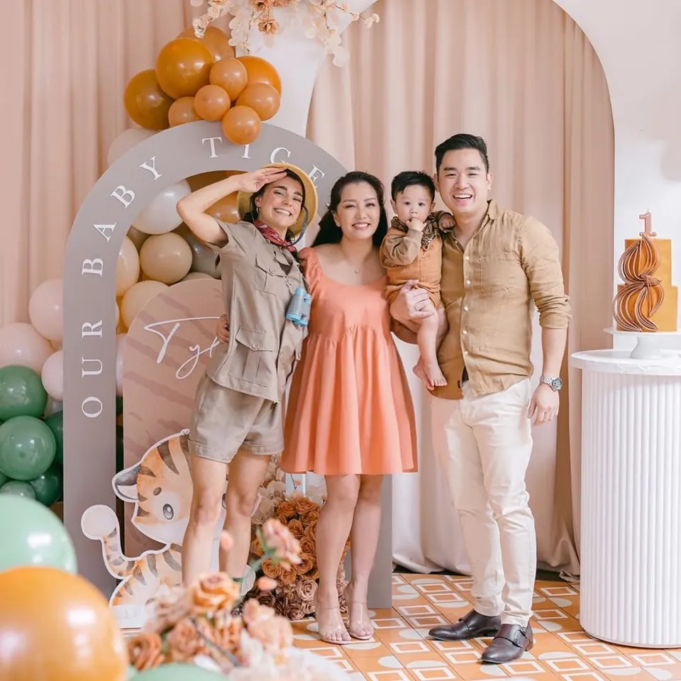 Safari explorer entertainer posing with family at 'Our Baby Tiger' jungle-themed first birthday party with balloon arch and tiger cake in Melbourne