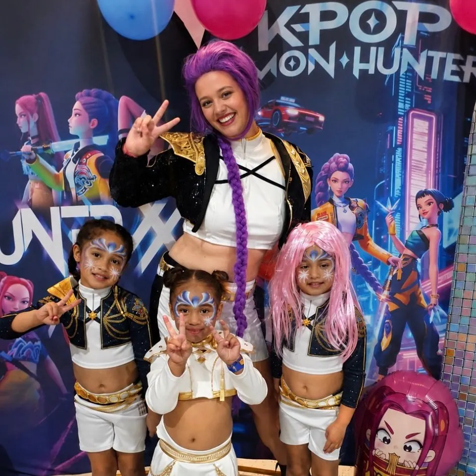 KPop Demon Hunters themed birthday party in Melbourne with Dreamscape entertainer in purple wig and three girls with matching face paint and costumes